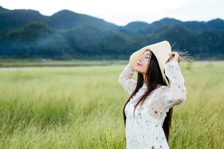 woman-who-is-holding-grass-her-hands-beautiful-grass-field-with-mountain-3080686757.jpg